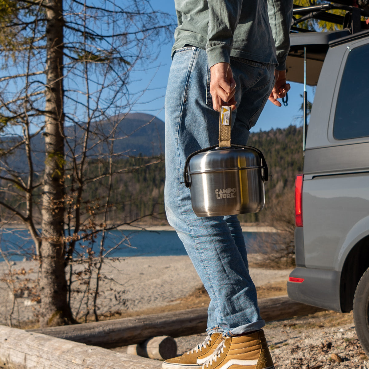 Mann trägt das gepackte Campo Libre Enzo L Camping-Kochset aus Edelstahl am Tragegurt neben einem Campervan am See, Outdoor-Küche für Vanlife und Camping