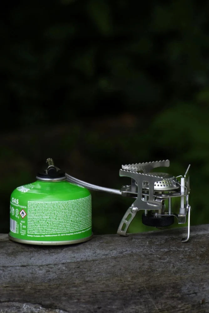 Detailaufnahme des Lambda Coffee Gaskochers Fuoco mit Anschluss an die Gaskartusche – kompakter Outdoor-Kocher für Camping & Vanlife