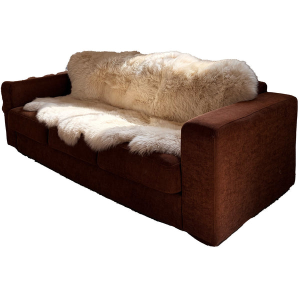 Beiges Merino Schaffell XXL mit 190 x 115 cm liegt ausgebreitet auf einer braunen Polstergarnitur im Wohnzimmer